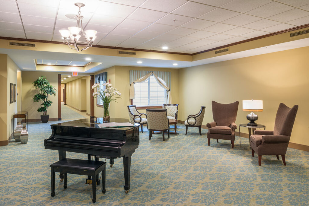 Second Floor Neighborhood sitting area with a piano table, a vase with white flowers in it, sofa chairs around small coffee tables.