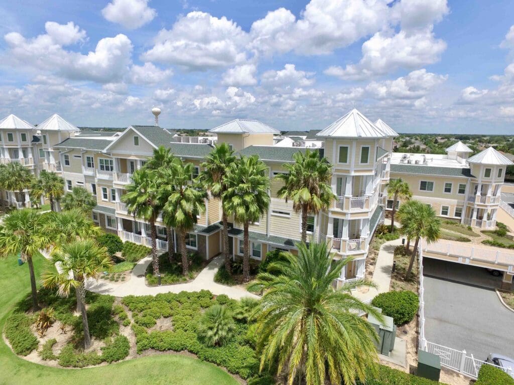 Sumter Senior Living main pale yellow and white building with palm trees in front of it.